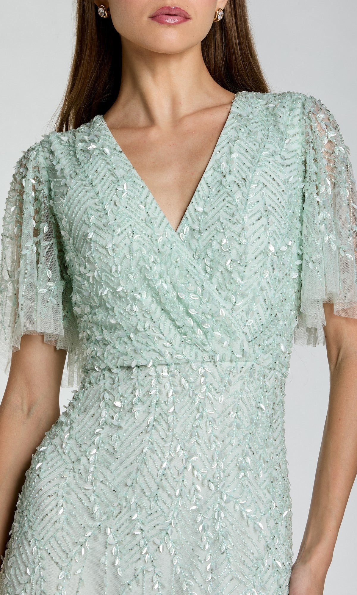 A woman wearing the Mac Duggal 35116 Beaded Midi Semi-Formal Dress in light green, featuring short sleeves, sequin and bead details, and a flattering V-neckline—ideal for any semi-formal event.